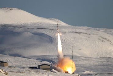 A rocket takes off from a field of ice and snow.