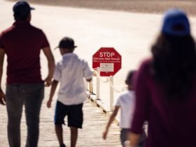 Visitors walk past a sign reading "Stop Extreme Heat Danger"