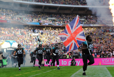 NFL players running onto a field with union jack flag