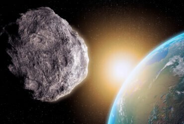 An asteroid floats in space in the foreground, with the Earth in the background.