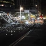 Crane sits on the street after crashing down into the building.