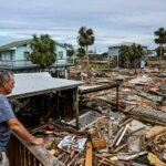 Man looking out to destroyed homes from his deck.