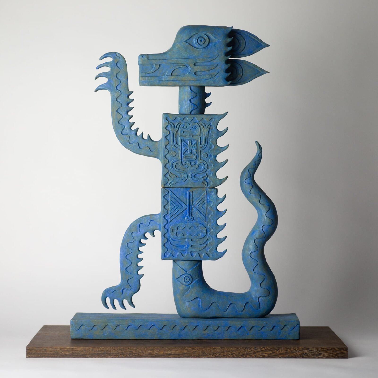 an abstract ceramic sculpture suggesting a dragon in profile, painted blue