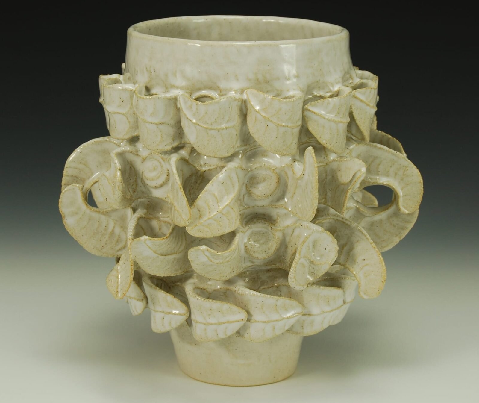 a ceramic vessel with leaf-like decorations that wrap around its body