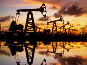 The silhouette of oil rigs among an orange and blue sky.