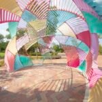 the interior of a colorful metal outdoor installation shaped like a dome with geometric facets