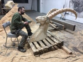 artist Quentin Garel working on a wooden sculpture of an ibex in his studio