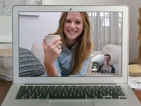 A woman on a computer screen smiles while she looks at a smaller square of a man, who is also smiling.