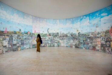 a woman stands in front of a round installation with various imagery