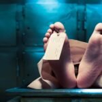 a body on a morgue table with only the feet showing and a toe tag on the big toe