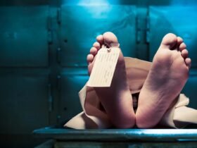 a body on a morgue table with only the feet showing and a toe tag on the big toe