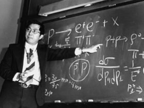 Physicist Samuel Ting points at equations on a blackboard that describe the subatomic particle J/psi.