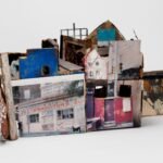 a sculpture of an abstract house made from ceramics, found objects, photographs, and other mixed media