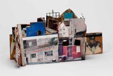 a sculpture of an abstract house made from ceramics, found objects, photographs, and other mixed media