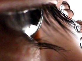 A closeup shows an eye framed by eyelashes, with four droplets of water pictured landing on an eyelash, sliding off, and falling.