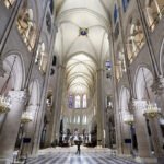 An image inside the Notre Dame cathedral shows a high vaulted ceiling and arches.