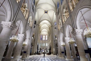 An image inside the Notre Dame cathedral shows a high vaulted ceiling and arches.