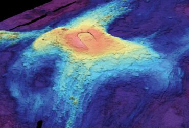 A heat map image of the ocean floor shows bloblike circles of red, yellow, and blues fading out from the volcano