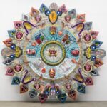 an abstract glass sculpture in the form of an Aztec calendar with numerous mixed-media details and patterns