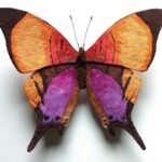 a strikingly realistic sculpture of a yellow and purple butterfly made from embroidery thread and wire