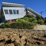 A wrecked house is in the background, while mud fills the foreground