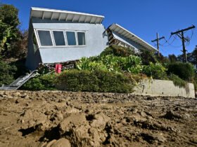 A wrecked house is in the background, while mud fills the foreground