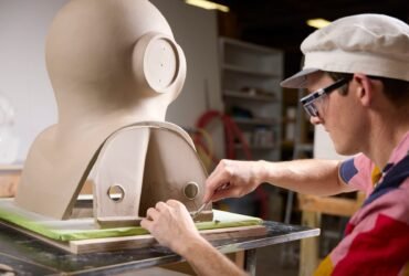 an artist works on a large almost figurative sculpture on a table