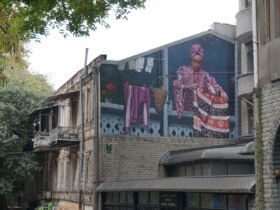 a large mural on the side of a building of a woman hanging out her laundry