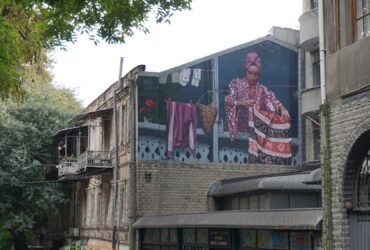 a large mural on the side of a building of a woman hanging out her laundry