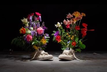 a still from an animated short of two canvas sneakers with flowers blossoming out of them, set against a black background