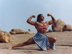 an indian woman in a a small checked bandeau top and blue and white checked skirt shows off her large muscles in a squat