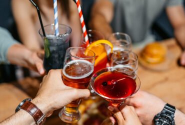 People raise their glasses of alcoholic drinks to toast each other.