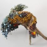 a botanical sculpture of bird, made from glass, wood, and ceramics