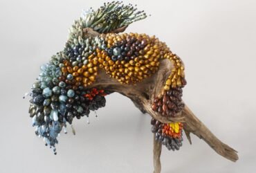 a botanical sculpture of bird, made from glass, wood, and ceramics