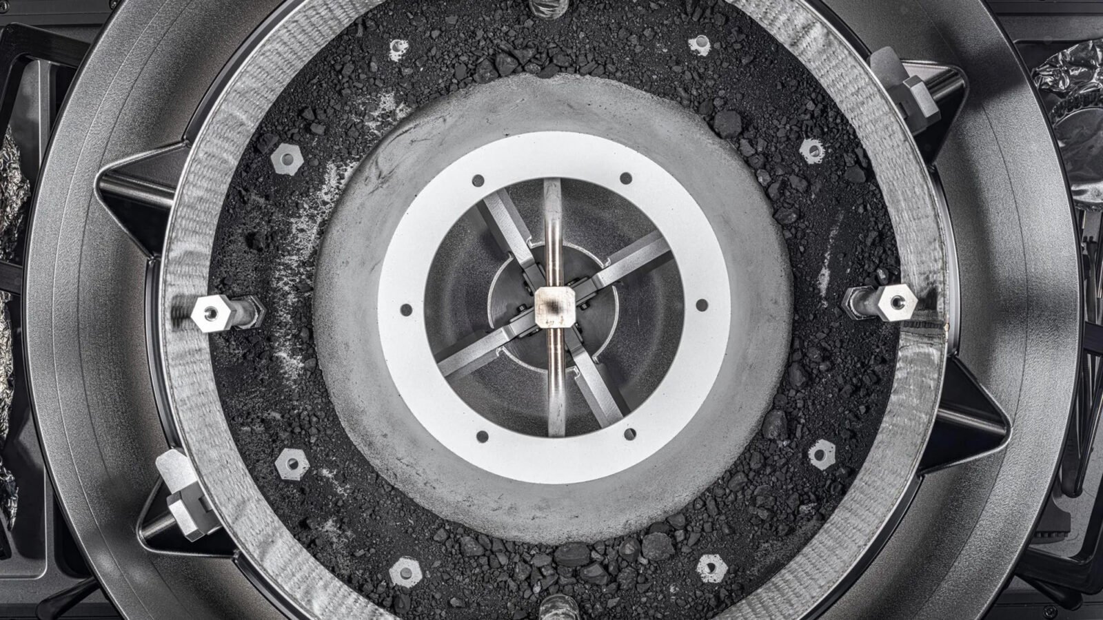 A top-down view of the OSIRIS-REx Touch-and-Go-Sample-Acquisition-Mechanism (TAGSAM) head with the lid removed, revealing the remainder of the asteroid sample inside. The picture was taken using manual high-resolution precision photography and a semi-automated focus stacking procedure. The result is an image that can be zoomed in on to show extreme detail of the sample. The remaining sample material includes dust and rocks up to about 0.4 inch in size.