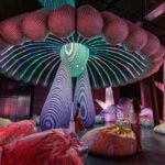 people stands beneath an illuminated installation with lights resembling the underside of a mushroom