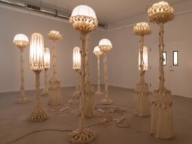 a group of sculptural white lamps made from pieces of fabric coated in bio resin and knotted, illuminated and displayed in a white gallery space