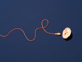 Orange Ear Plugs with Curved String Reach to Ear on Blue Background Directly above View. 4 tips for RevOps teams to filter out the noise and focus on the big picture