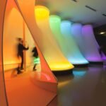 a large-scale fabric installation in a museum with different segments illuminated in the colors of a prism