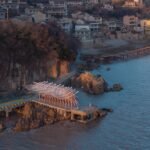 an aerial view of a seaside pavilion made of white feather-like blades