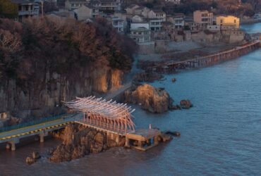 an aerial view of a seaside pavilion made of white feather-like blades