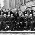 A black and white photo of nearly 30 physicists, most seated, some standing, posing for the camera.