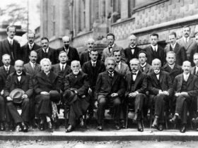 A black and white photo of nearly 30 physicists, most seated, some standing, posing for the camera.