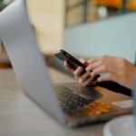 Woman working on laptop and phone