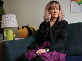 A photo of a woman sitting on a couch looking at the camera.