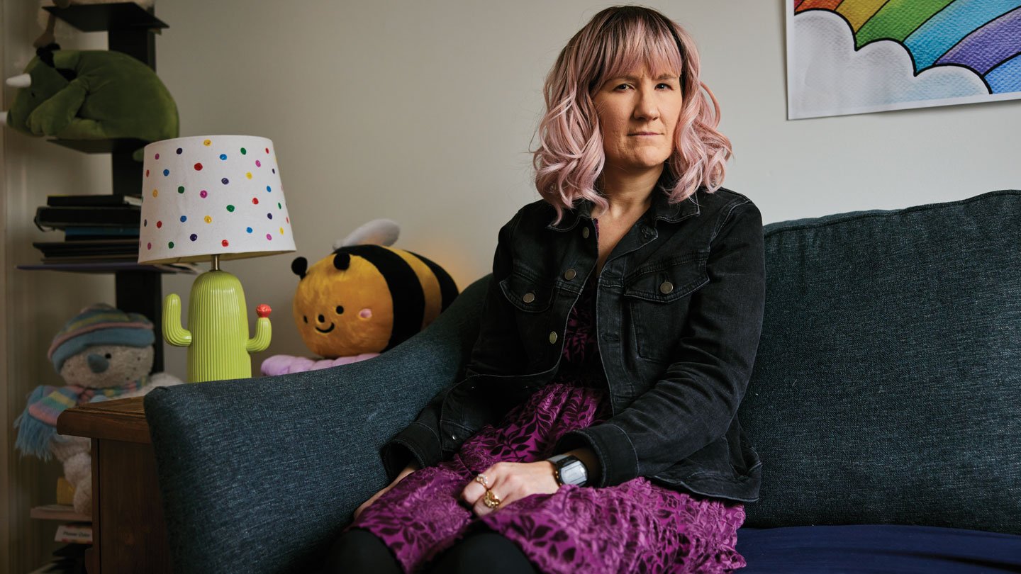 A photo of a woman sitting on a couch looking at the camera.