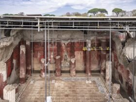 an overview from an elevated perspective of a large-scale fresco in a banquet hall excavated in Pompeii, supported by scaffolding and metal bars