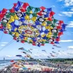 a massive vibrant kite in the sky above a beach