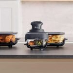 The portable air fryer in three different colours on a counter