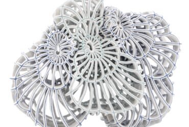 an abstract ceramic sculpture with blue porcelain and white flocked-like surfaces with numerous spokes and irregular concentric circles